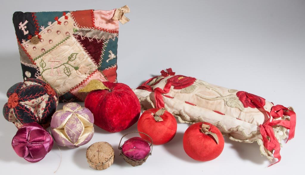 VARIOUS FABRIC AND FIGURAL PIN CUSHIONS, LOT OF TEN: VARIOUS FABRIC AND FIGURAL PIN CUSHIONS, LOT OF TEN, comprising three apple forms, two baskets including a brass example with a handle and a sweet grass example, three ball-form examples, two pillow-f