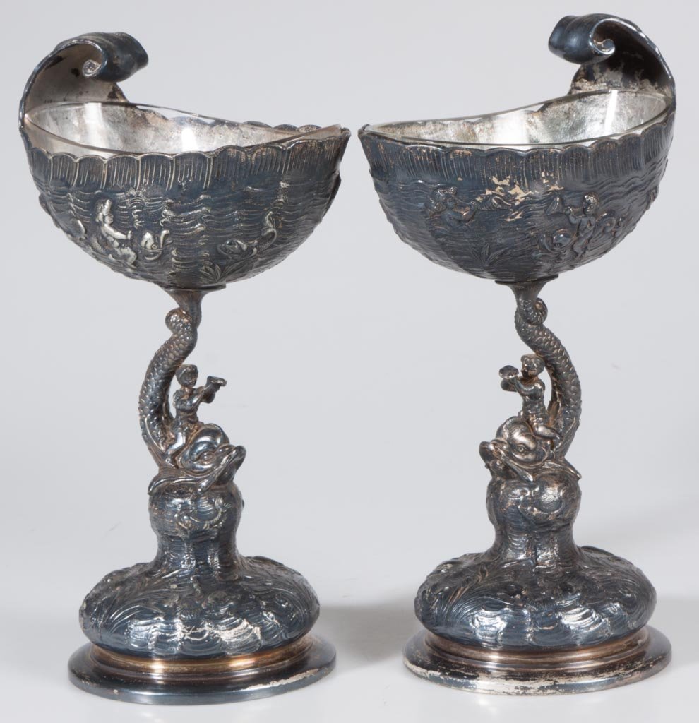 PAIRPOINT QUADRUPLE-PLATE PAIR OF FIGURAL COMPOTES: PAIRPOINT QUADRUPLE-PLATE PAIR OF FIGURAL COMPOTES, each glass-lined shell-form bowl embossed with cherubs riding dolphins, raised on a dolphin and rider standard and cushion-like base with additional
