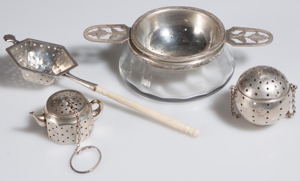 AMERICAN STERLING SILVER TEAWARES, LOT OF FOUR: AMERICAN STERLING SILVER TEAWARES, LOT OF FOUR, comprising a Merrill Shops two handle strainer with glass stand, a bone handle strainer, and two tea balls. 20th century. Largest 4 7/8" W. Provenance: 