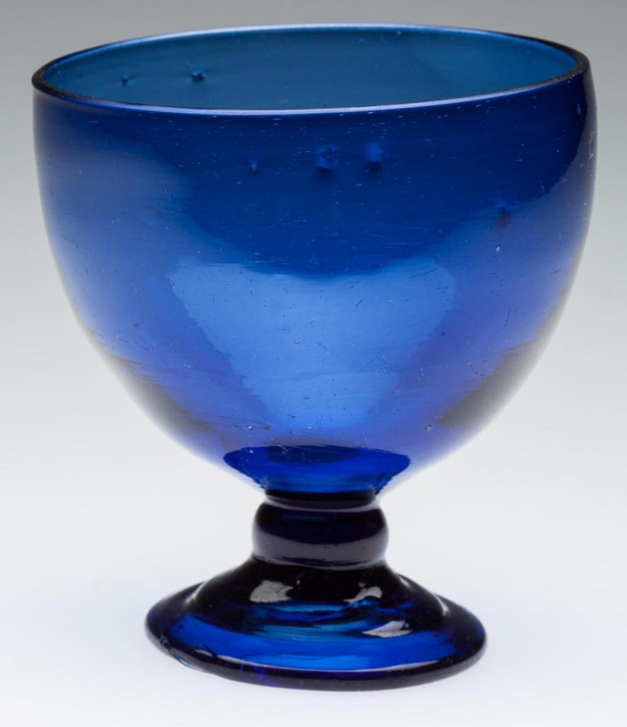 FREE-BLOWN OPEN SUGAR BOWL: FREE-BLOWN OPEN SUGAR BOWL, cobalt blue with undisolved metal and striations, deep bowl with plain rim, raised on a drawn-knop stem and applied thick sloping foot with rough pontil mark. Late 18th/ear