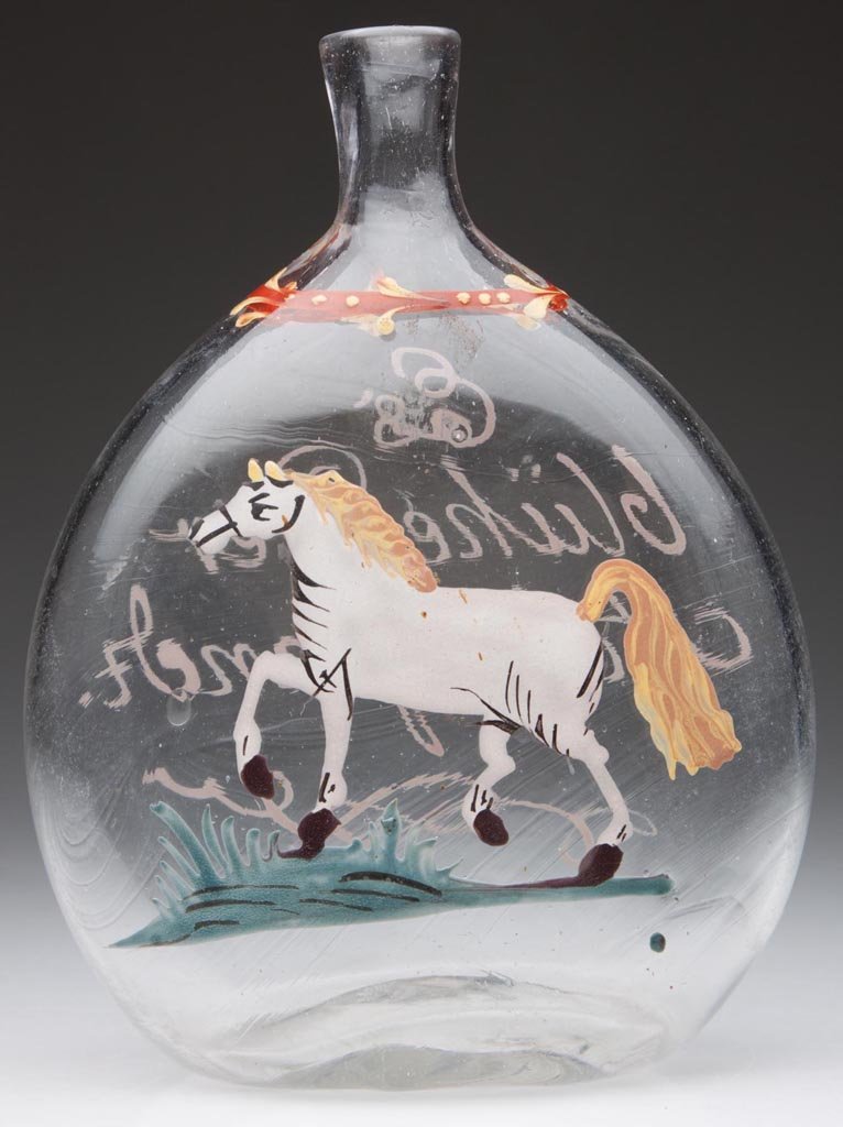 FREE-BLOWN AND DECORATED "STIEGEL-TYPE" POCKET FLASK: FREE-BLOWN AND DECORATED "STIEGEL-TYPE" POCKET FLASK, colorless, flattened chestnut form with polychrome enamel decoration featuring a trotting horse on front and inscribed "Es bluhe der Ackerstand" o
