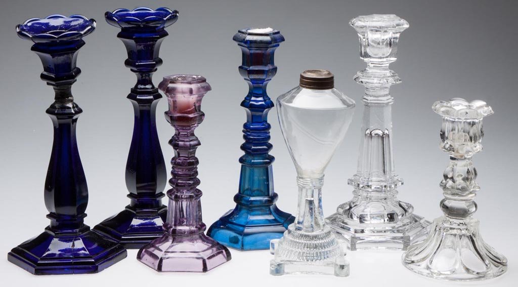 ASSORTED GLASS LIGHTING DEVICES, LOT OF SEVEN: ASSORTED GLASS LIGHTING DEVICES, LOT OF SEVEN, comprising four colored candlesticks, two colorless candlesticks, and a free-blown and pressed whale oil lamp. Boston & Sandwich Glass Co. and others. Fi
