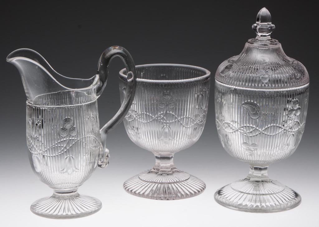 BELLFLOWER - DOUBLE VINE TABLE ARTICLES, LOT OF THREE: BELLFLOWER - DOUBLE VINE TABLE ARTICLES, LOT OF THREE, colorless lead glass, all vines flow right, comprising a creamer with applied solid handle and 36 rays under the foot, two sugar bowls and one co