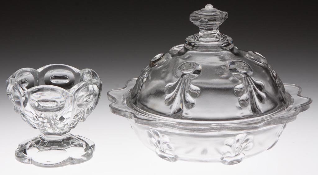 BULL'S EYE WITH FLEUR DE LYS TABLE ARTICLES, LOT OF TWO: BULL'S EYE WITH FLEUR DE LYS TABLE ARTICLES, LOT OF TWO, colorless lead glass, comprising a covered butter dish with hexagonal finial and scalloped rim, and an open master salt raised on a six-scallop