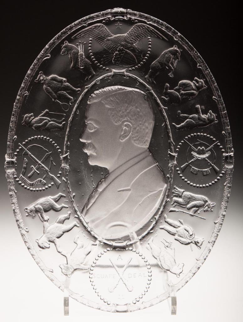 THEODORE ROOSEVELT OVAL PLATTER: THEODORE ROOSEVELT OVAL PLATTER, colorless, frosted bust in center, bears and military symbols around edge, embossed "A SQUARE DEAL". Fourth quarter 19th century. 7 3/4" x 10 3/8". Literature: Lindsey