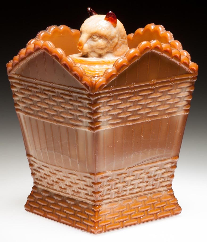 GREENTOWN CAT ON HAMPER - TALL / BASKET AND COVER (OMN): GREENTOWN CAT ON HAMPER - TALL / BASKET AND COVER (OMN) COVERED DISH, chocolate, with red agate cover. Indiana Tumbler & Goblet Co. Early 20th century. 4 3/4" HOA, 3 1/2" SQ OA. Literature: NGGA/Mease