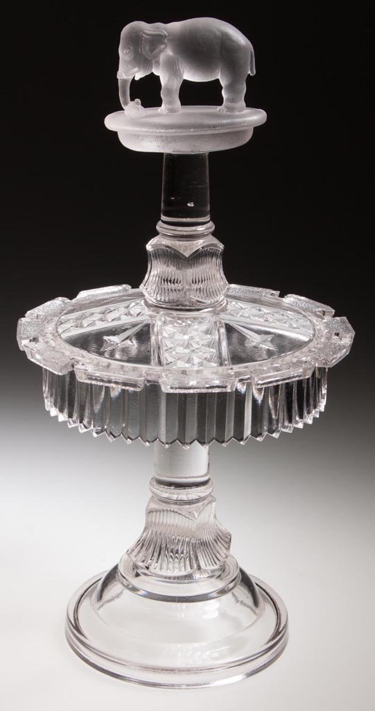 JUMBO SPOON RACK: JUMBO SPOON RACK, colorless with frosted finish to elephant and platform, without embossed patent date. Canton Glass Co. Fourth quarter 19th century. 11 1/4" H, 6" D. Provenance: From the Rudolph Ever