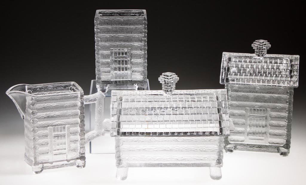 LOG CABIN FOUR-PIECE TABLE SET: LOG CABIN FOUR-PIECE TABLE SET, colorless, comprising a covered butter dish, covered sugar bowl, creamer and spooner. Central Glass Co. Fourth quarter 19th century. 4 3/4" to 7" HOA, 2 1/2" x 3 1/8" t