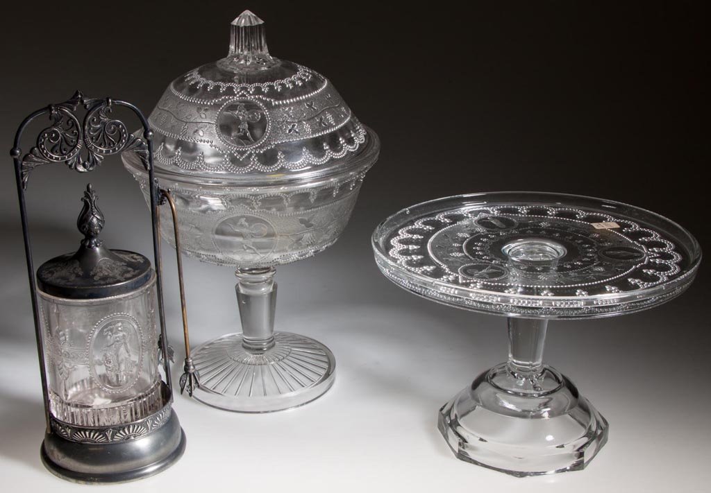 ASSORTED EAPG TABLE ARTICLES, LOT OF THREE: ASSORTED EAPG TABLE ARTICLES, LOT OF THREE, colorless, comprising a Minerva covered compote and cake stand, along with a Cupid and Venus pickle jar in quadruple-plate frame with manufacturer's mark. F