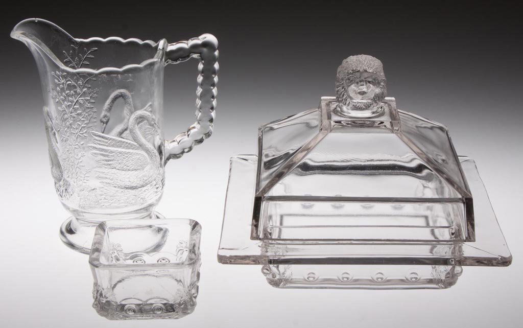 ASSORTED ANIMAL EAPG TABLE ARTICLES, LOT OF THREE: ASSORTED ANIMAL EAPG TABLE ARTICLES, LOT OF THREE, colorless, comprising a Paneled Swan/Swan with Fish creamer, and a Fostoria Atlanta/Square Lion covered butter dish and square master salt. Fourth qu