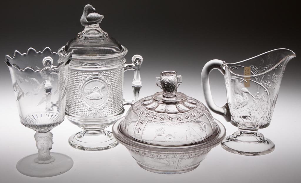 ASSORTED EAPG TABLE ARTICLES, LOT OF FOUR: ASSORTED EAPG TABLE ARTICLES, LOT OF FOUR, colorless, comprising a Clear Stork creamer, a Three face engraved spooner with frosted figural stem, an Egyptian butter dish, and a Swan/Netted Swan covered