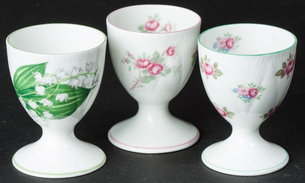 ENGLISH PORCELAIN SHELLEY CHINA LTD., THREE EGG CUPS "B: ENGLISH PORCELAIN SHELLEY CHINA LTD., THREE EGG CUPS "BRIDAL ROSE"; "ROSEBUD" AND "LILY OF THE VALLEY" PATTERNS, AND "DAINTY" SHAPE, all of tapering shape with cylindrical flaring base below the ankle