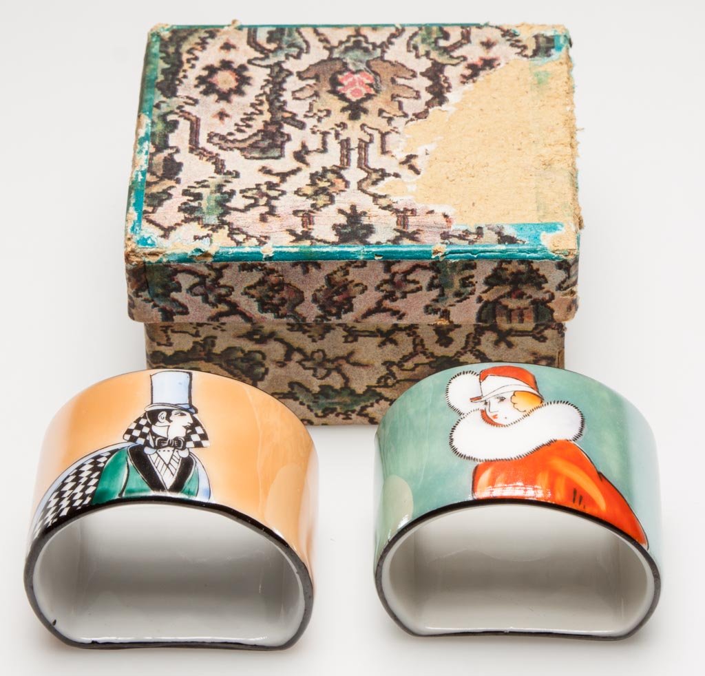 JAPANESE PORCELAIN NORITAKE PORCELAIN ART DECO PERIOD P: JAPANESE PORCELAIN NORITAKE PORCELAIN ART DECO PERIOD PAIR OF NAPKIN RINGS IN THEIR ORIGINAL BOX, the rings formed as semi-circular bands, handpainted with stylish male and female figures in appropria