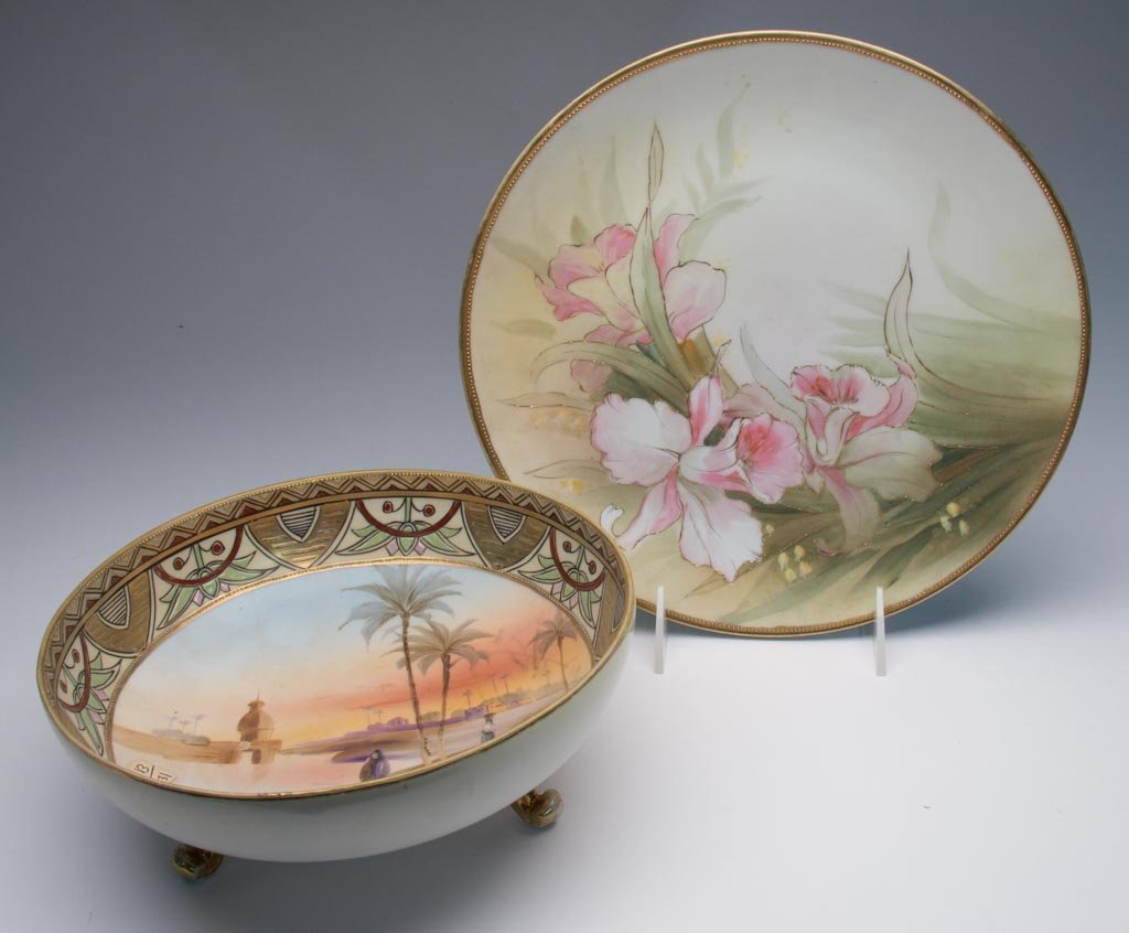 JAPANESE PORCELAIN NIPPON PORCELAIN EGYPTIAN-REVIVAL FO: JAPANESE PORCELAIN NIPPON PORCELAIN EGYPTIAN-REVIVAL FOOTED BOWL, with band of geometric motifs over stylized lotus motifs alternating with gilt patterns, centering an exotic landscape featuring peopl
