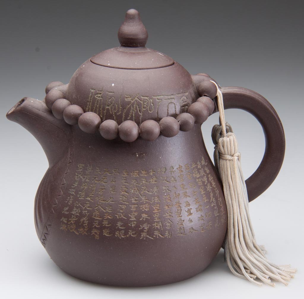 CHINESE YIXING ZISHA CLAY ARTISTIC DARK-BROWN TEAPOT AN: CHINESE YIXING ZISHA CLAY ARTISTIC DARK-BROWN TEAPOT AND COVER, the body formed as an eggplant, with a thick handle and slightly-arcing spout, a band of fully-articulated beads on a string attached to