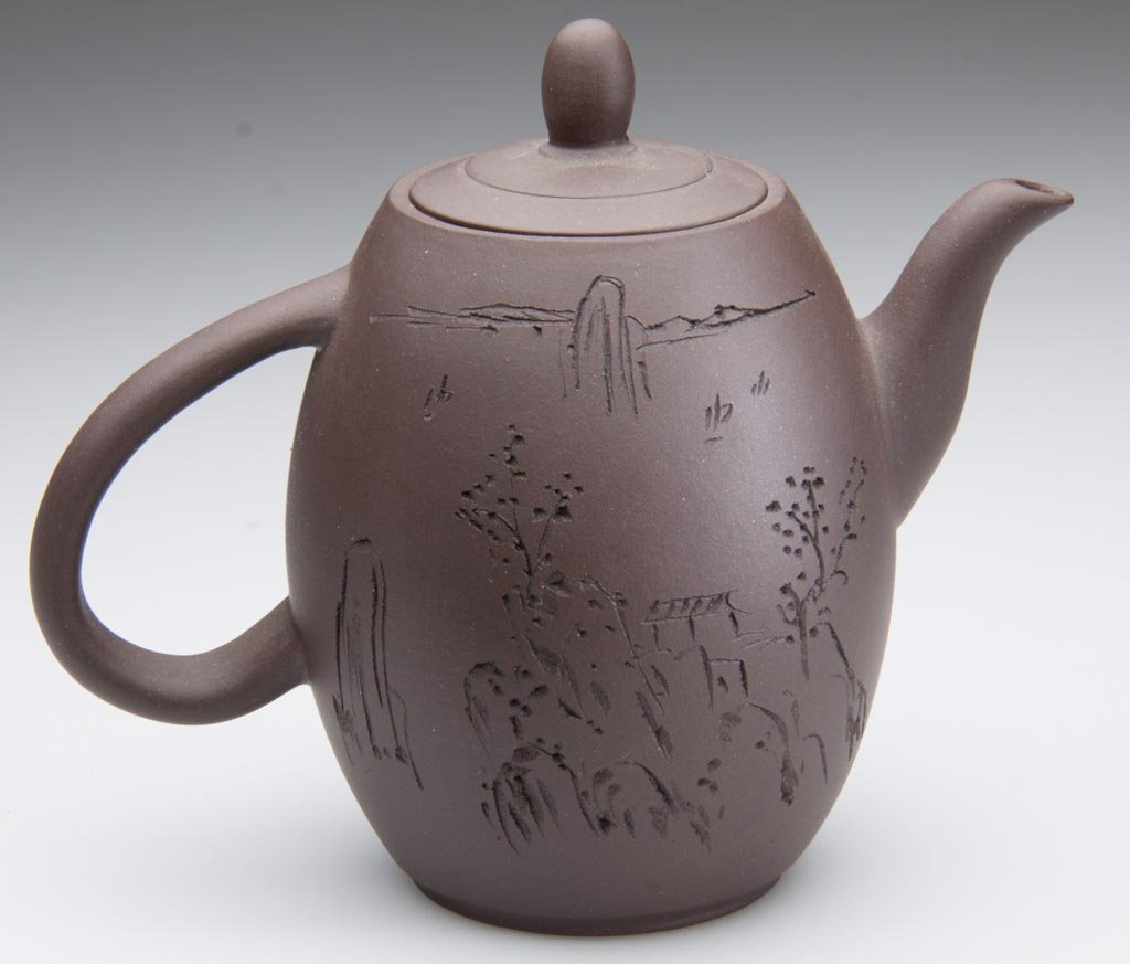 CHINESE YIXING ZISHA CLAY ARTISTIC DARK-BROWN STONEWARE: CHINESE YIXING ZISHA CLAY ARTISTIC DARK-BROWN STONEWARE TEAPOT AND COVER, the elongated globular body very simply molded, the handle purposely attached upside-down, the spout gently curved, the cover 