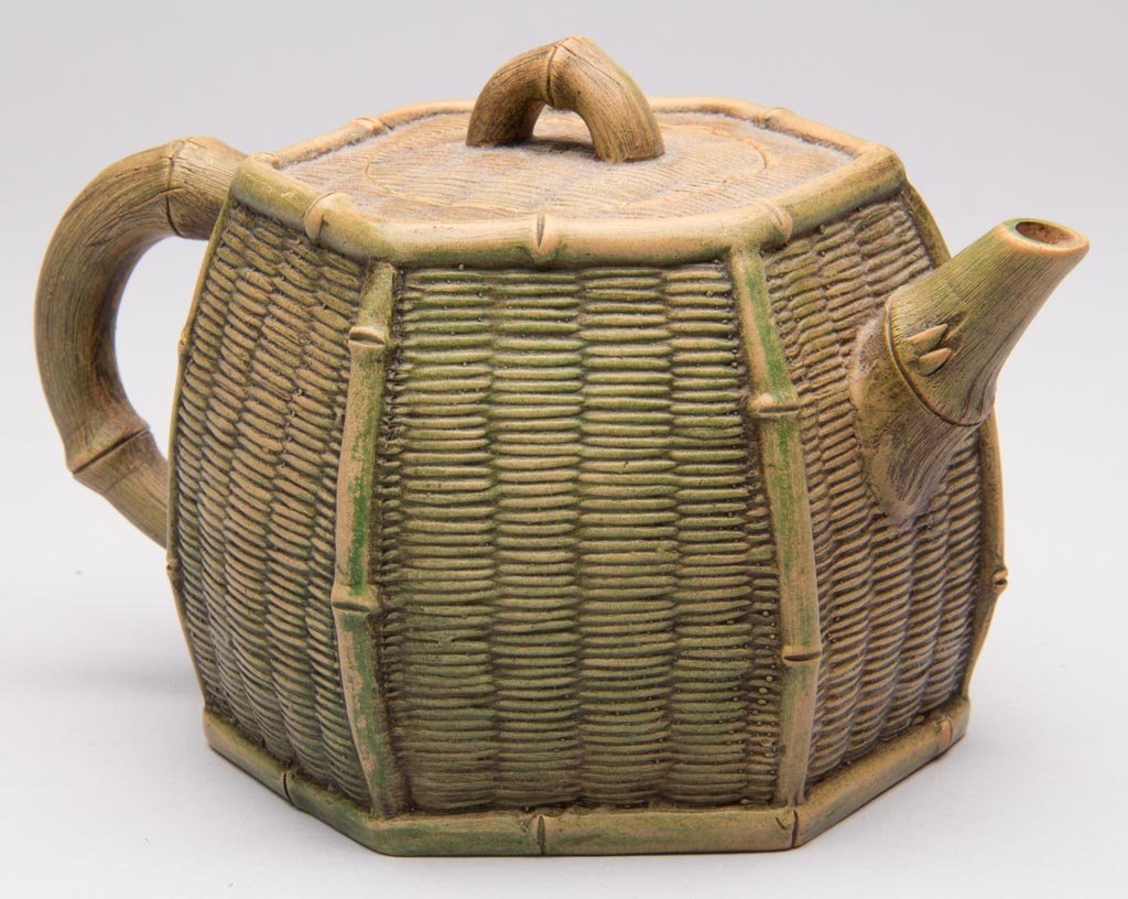 CHINESE YIXING ZISHA CLAY ARTISTIC LIGHT-BROWN TEAPOT A: CHINESE YIXING ZISHA CLAY ARTISTIC LIGHT-BROWN TEAPOT AND COVER, in the form of an ovoid hexagonal wicker basket with bamboo handle, spout and knop to cover, impressed seal mark to underside. People's