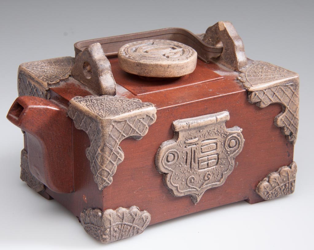 PEOPLE'S REPUBLIC OF CHINA YIXING ZISHA CLAY ARTISTIC T: PEOPLE'S REPUBLIC OF CHINA YIXING ZISHA CLAY ARTISTIC TEAPOT AND COVER, formed to resemble a storage chest, the red-brown body of rectangular brick form, applied with buff-color faux corner brackets, 