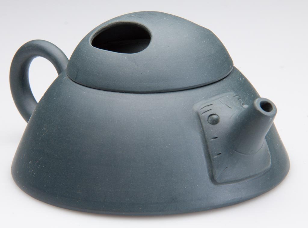 CHINESE YIXING ZISHA CLAY ARTISTIC TEAL-BLUE TEAPOT AND: CHINESE YIXING ZISHA CLAY ARTISTIC TEAL-BLUE TEAPOT AND COVER, the squat body of flaring, cylindrical form, with simple tube-form handle to back, the front, with an applied geometric mask of animate f