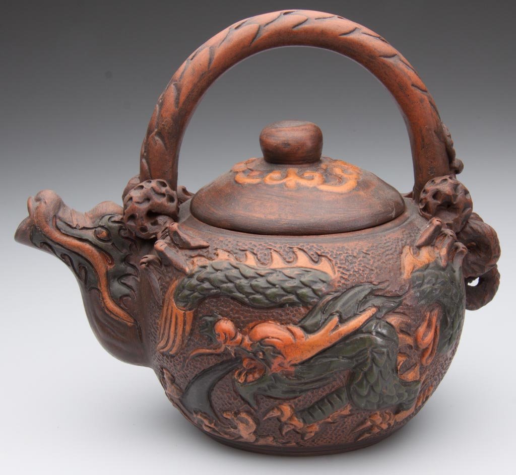 CHINESE POTTERY YIXING ZISHA CLAY TWO-TONE TEAPOT AND C: CHINESE POTTERY YIXING ZISHA CLAY TWO-TONE TEAPOT AND COVER, the red-brown globular body with stylized dragon's head forming the spout; its tail, forming the handle, the sides molded in low relief wit