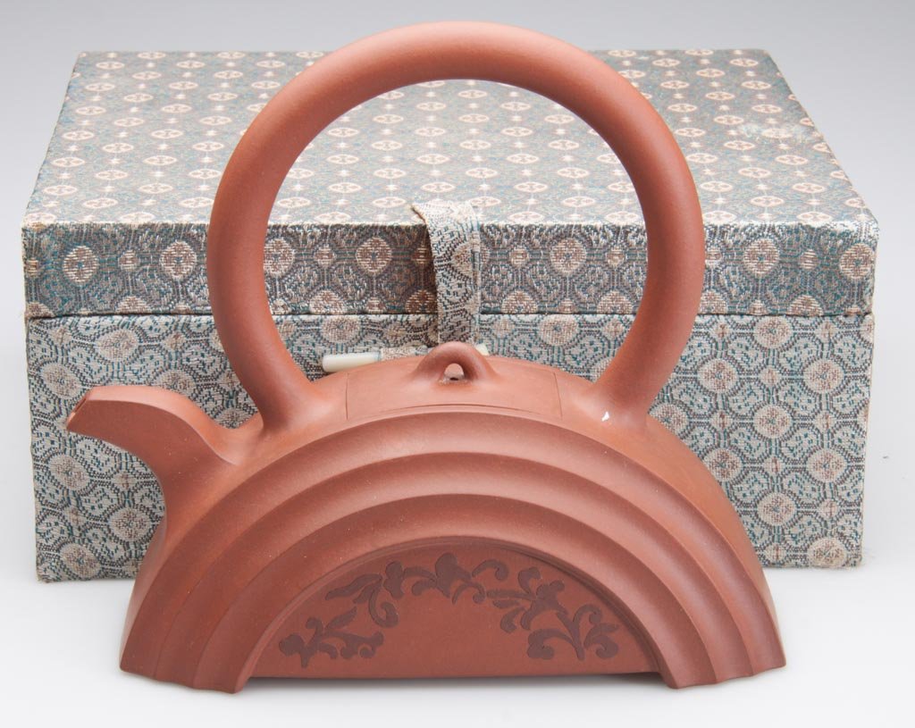 CHINESE YIXING ZISHA CLAY ARTISTIC TEAPOT AND COVER, TH: CHINESE YIXING ZISHA CLAY ARTISTIC TEAPOT AND COVER, THE, body formed as a flat-based hemisphere, the tubular handle arcing over the top, the rectangular cover inset into the top, with a simple loop k