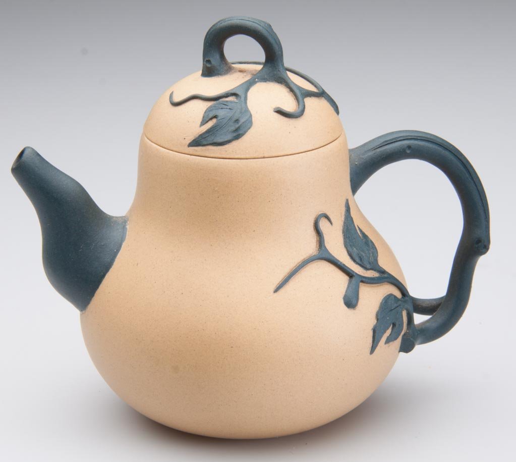 CHINESE YIXING ZISHA CLAY ARTISTIC MINIATURE LIGHT-BROW: CHINESE YIXING ZISHA CLAY ARTISTIC MINIATURE LIGHT-BROWN TEAPOT AND COVER, the body formed as an elongated squash, with dark green curling stem forming the handle and spout, the cover with U-form knop
