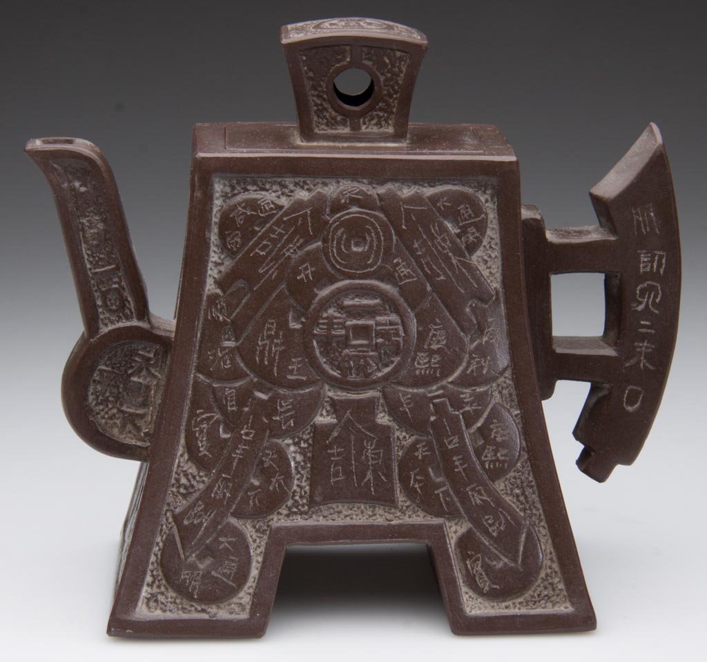 CHINESE YIXING ZISHA CLAY POTTERY ARTISTIC DARK-BROWN T: CHINESE YIXING ZISHA CLAY POTTERY ARTISTIC DARK-BROWN TEAPOT AND COVER, molded to resemble a temple gate, with Chinese characters molded in low relief to the sides, the handle of geometric form, the k
