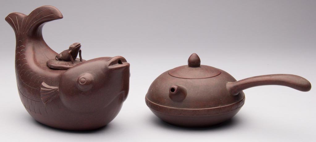 CHINESE YIXING ZISHA CLAY ARTISTIC POLISHED BROWN STONE: CHINESE YIXING ZISHA CLAY ARTISTIC POLISHED BROWN STONEWARE TEAPOTS AND COVERS, LOT OF TWO, the first, formed as a fish with an arching tail, with frog atop a lotus leaf forming the cover, with incise
