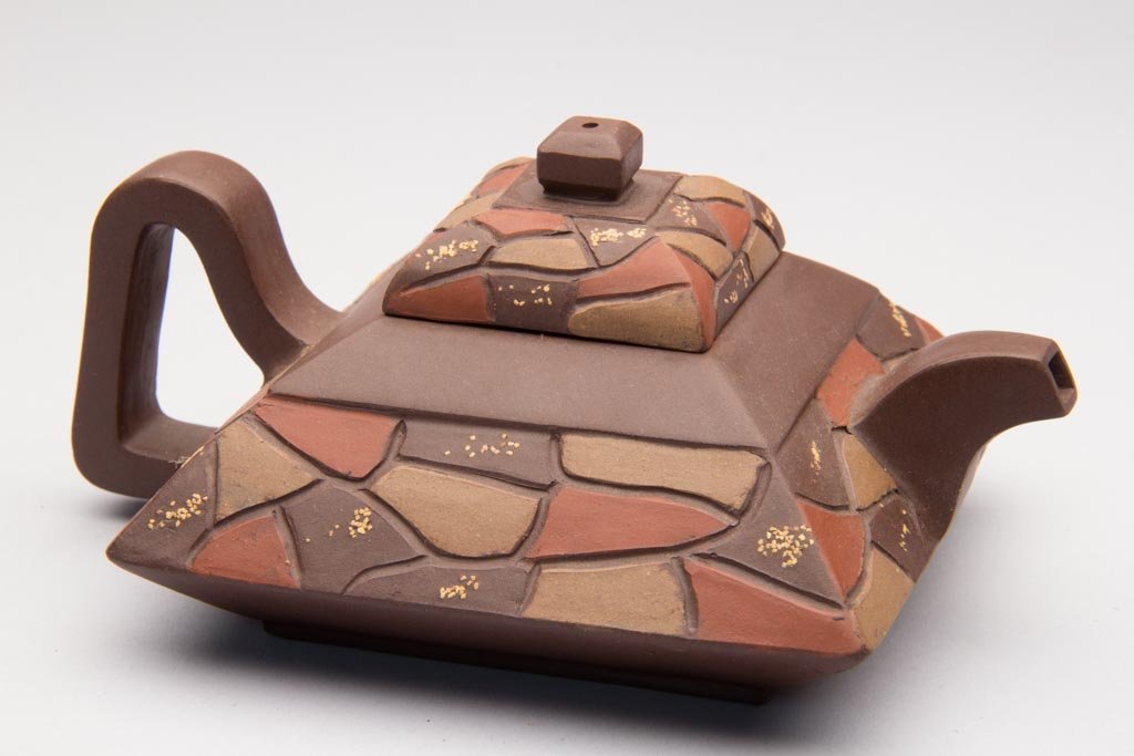 CHINESE YIXING ZISHA CLAY ARTISTIC TEAPOT AND COVER: CHINESE YIXING ZISHA CLAY ARTISTIC TEAPOT AND COVER, of squat, flaring square form, with a low, mounded cover, the handle, spout and finial of strap and squared form, the sides of the pot and the body