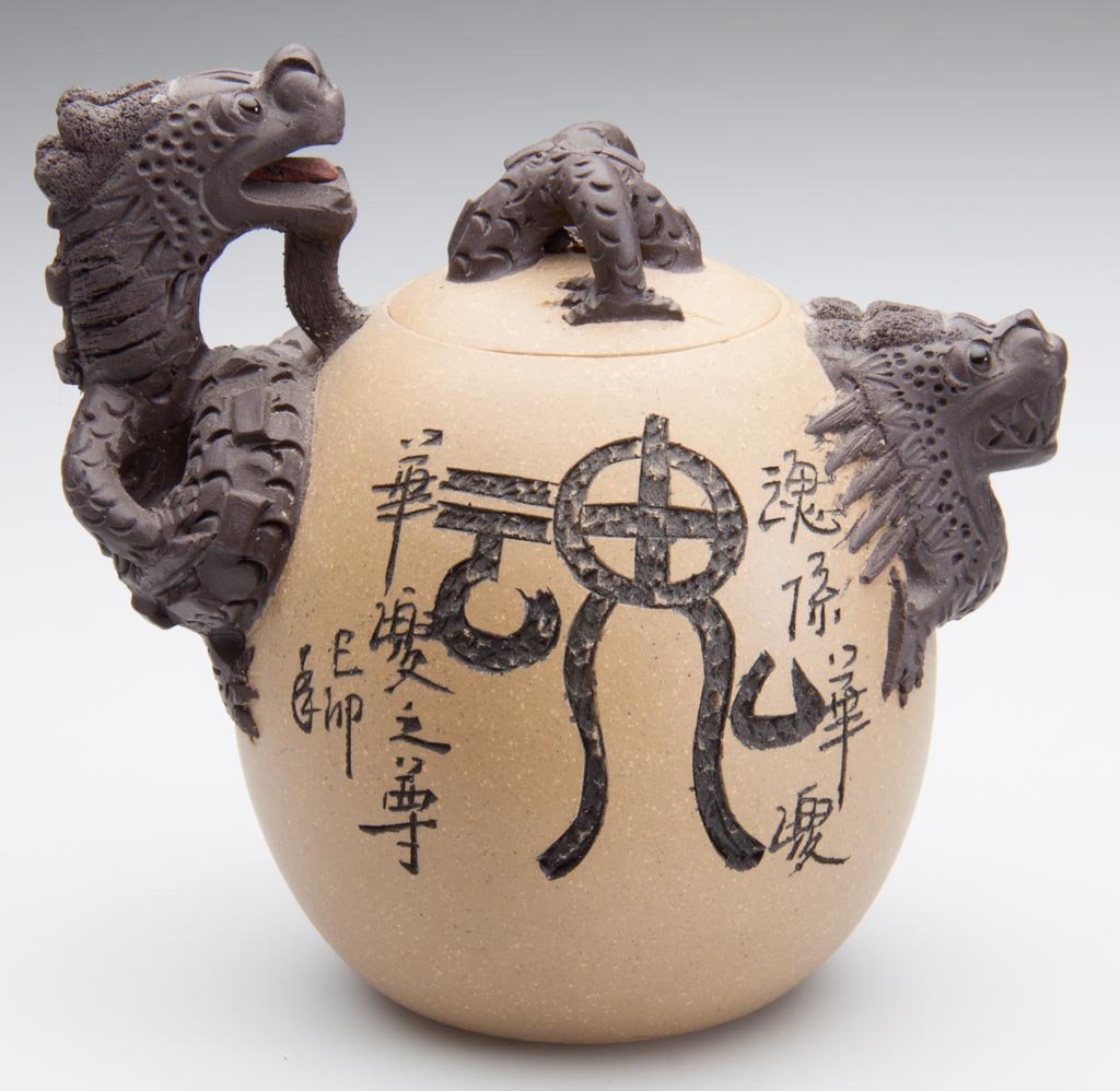 CHINESE YIXING ZISHA CLAY ARTISTIC TWO-TONE TEAPOT AND : CHINESE YIXING ZISHA CLAY ARTISTIC TWO-TONE TEAPOT AND COVER, OF, the light-brown body of ovate form, the handle and spout of dark-brown clay, formed as dragon heads, with claws grasping the teapot si