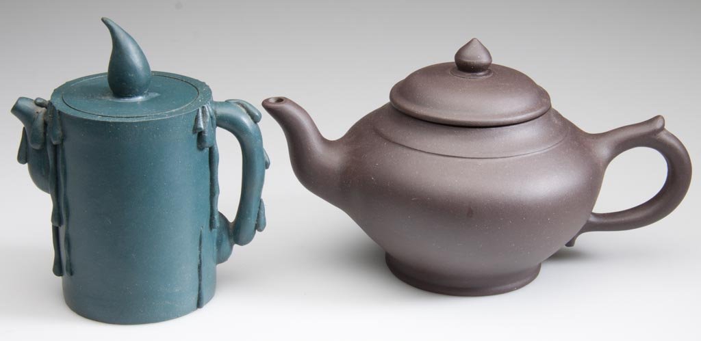 CHINESE YIXING ZISHA CLAY ARTICLES, LOT OF TWO: AN ARTI: CHINESE YIXING ZISHA CLAY ARTICLES, LOT OF TWO: AN ARTISTIC BLUE CANDLE-FORM TEAPOT AND COVER, WITH FLAMIFORM KNOP, the sides decorated with faux wax drips, and a brown clay very simple, round teapot,