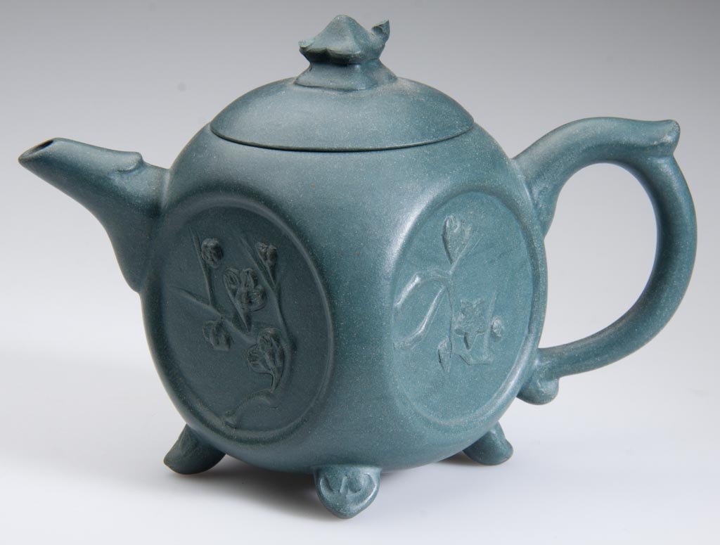 CHINESE YIXING ZISHA CLAY ARTISTIC TEAL-BLUE TEAPOT: CHINESE YIXING ZISHA CLAY ARTISTIC TEAL-BLUE TEAPOT, of rounded-square form, impressed with four ovular cartouches with low-relief flowering branches, on four pad feet. People's Republic of China. Lat