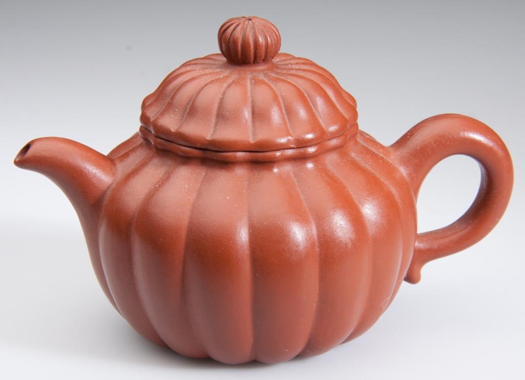 CHINESE YIXING ZISHA CLAY POTTERY ARTISTIC RED TEAPOT A: CHINESE YIXING ZISHA CLAY POTTERY ARTISTIC RED TEAPOT AND COVER, of squash-form, with ribbed sides, cover and button-shaped knop, with loop handle and curving spout, impressed seal mark to underside. 