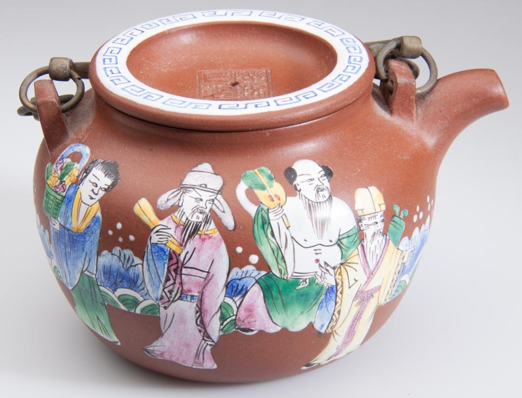 CHINESE YIXING ZISHA CLAY POTTERY ARTISTIC RED AND POLY: CHINESE YIXING ZISHA CLAY POTTERY ARTISTIC RED AND POLYCHROME ENAMELED TEAPOT AND COVER, of globular form, with lug-form anchors for two brass handles, brightly-enameled to the side in Chinese Export 