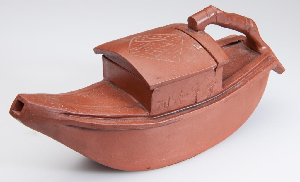 CHINESE YIXING ZISHA CLAY ARTISTIC POLISHED RED TEAPOT : CHINESE YIXING ZISHA CLAY ARTISTIC POLISHED RED TEAPOT AND COVER, in the form of a Chinese boat, with calligraphic mark to the cover, and impressed seal to the underside of the body. People's Republic