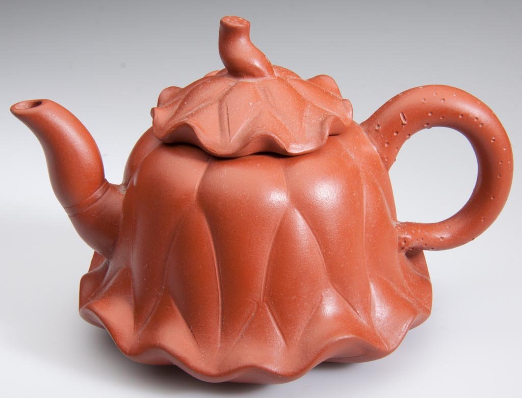 CHINESE YIXING ZISHA CLAY POTTERY ARTISTIC RED TEAPOT A: CHINESE YIXING ZISHA CLAY POTTERY ARTISTIC RED TEAPOT AND COVER, in the form of a flowering squash blossom, with undulating rims to foot and cover, the handle, spout and knop formed as roots, all with