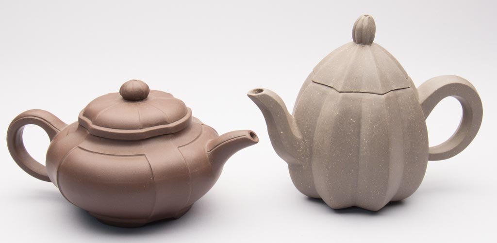 CHINESE YIXING ZISHA CLAY ZISHA CLAY ARTISTIC TEAPOTS, : CHINESE YIXING ZISHA CLAY ZISHA CLAY ARTISTIC TEAPOTS, LOT OF TWO, the first, a red globular example molded with four panels to the sides, with quatre-lobed cover and flattened, incised bead knop, the