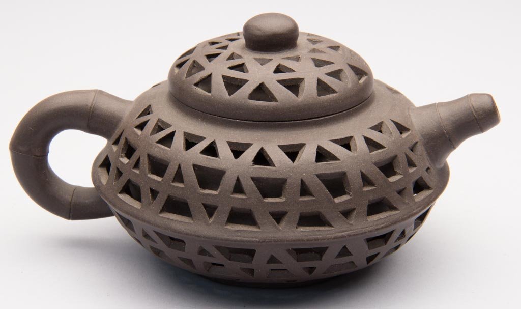 CHINESE YIXING ZISHA CLAY ARTISTIC DOUBLE-WALLED, RETIC: CHINESE YIXING ZISHA CLAY ARTISTIC DOUBLE-WALLED, RETICULATED DARK-BROWN TEAPOT AND COVER, the squat, globular body reticulated all over with triangles to resemble a basket; with bamboo-form handle an