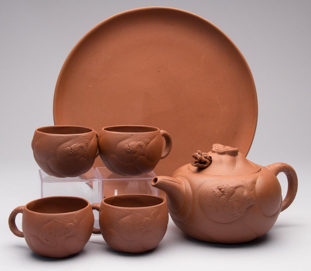 CHINESE YIXING ZISHA CLAY ARTISTIC RED TEASET: CHINESE YIXING ZISHA CLAY ARTISTIC RED TEASET, including teapot and cover, four teabowls and a tray, the teapot and cups molded with a dragon in incised and low-molded clouds, the arched knop with clo