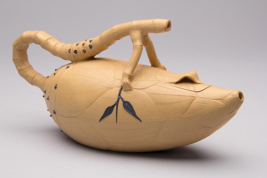 CHINESE YIXING ZISHA CLAY ARTISTIC LIGHT-BROWN TEAPOT A: CHINESE YIXING ZISHA CLAY ARTISTIC LIGHT-BROWN TEAPOT AND COVER, in the shape of a mango, with praying mantis-form curling root handle, the body delicately-incised with lines, and to either side of th