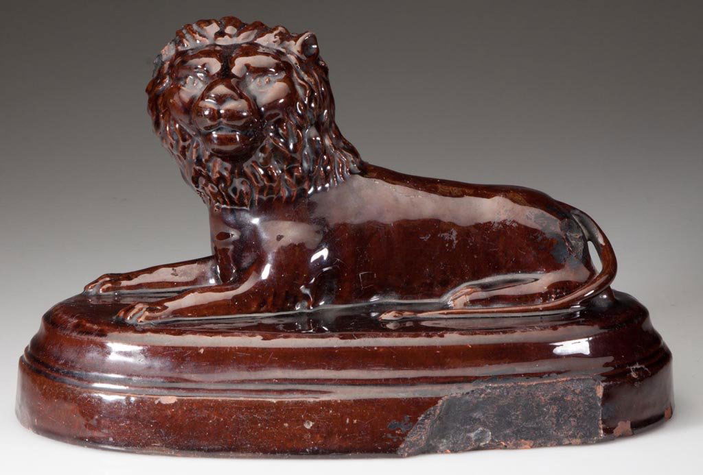 PRESS-MOLDED EARTHENWARE / REDWARE LION FIGURE: PRESS-MOLDED EARTHENWARE / REDWARE LION FIGURE, lead glazed, recumbent form on oval base, incised "Frederick" on base verso, mostly illegible inscription under base includes 1897. Late 19th century. 6
