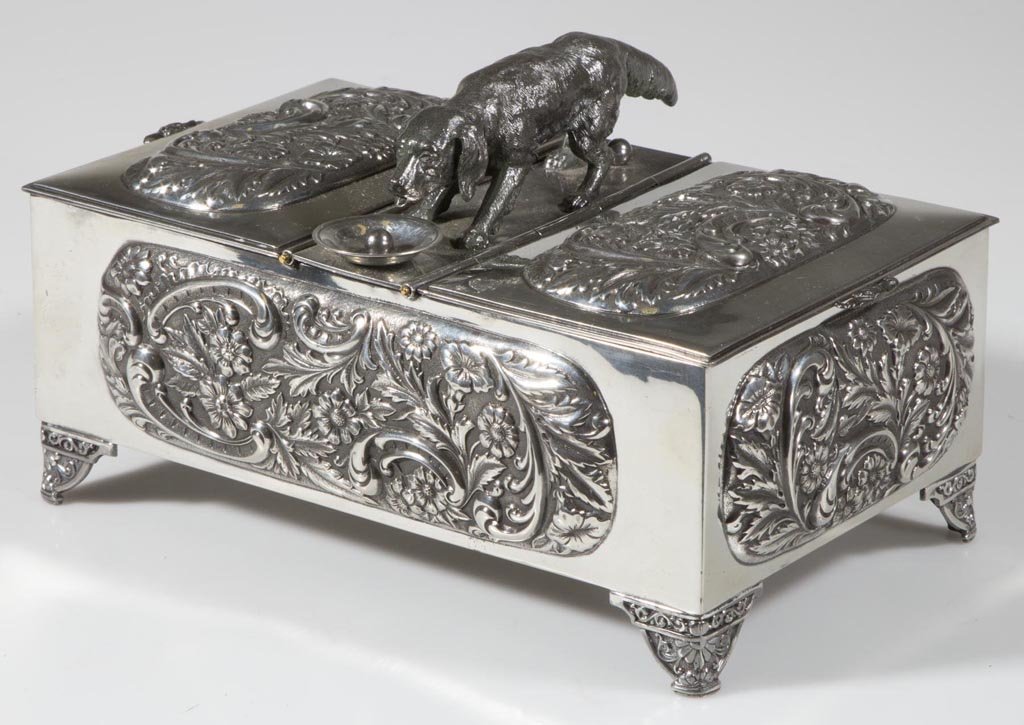 VICTORIAN QUADRUPLE-PLATE SILVER FIGURAL CIGAR BOX: VICTORIAN QUADRUPLE-PLATE SILVER FIGURAL CIGAR BOX, rectangular form with repousse floral decoration and a central figure of a dog drinking from a dish, flanked by two hinged lifting lids, raised on f