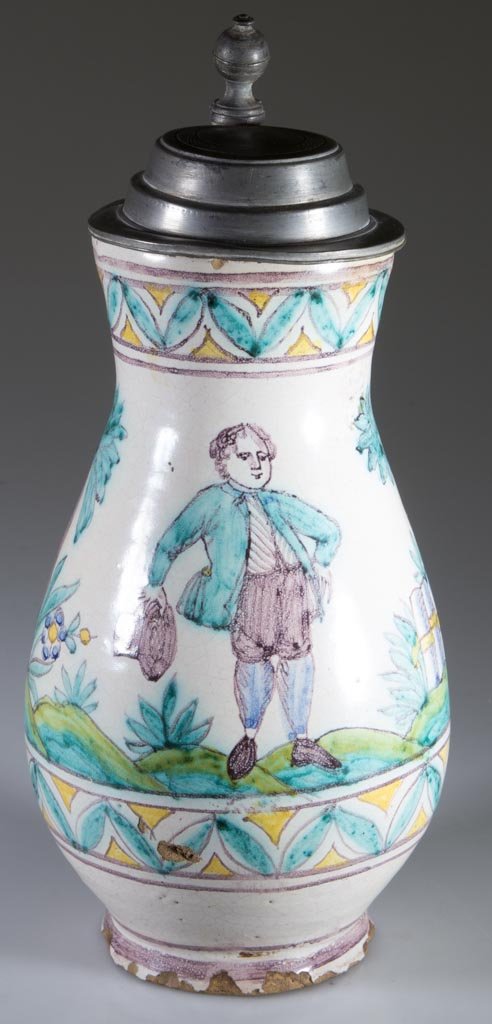 CONTINENTAL FAIENCE TANKARD WITH BRITTANIA COVER: CONTINENTAL FAIENCE TANKARD WITH BRITTANIA COVER, the baluster-form body with a modestly-flared foot, the strap handle with a curl to the terminate, the sides painted in manganese, yellow, green, blue