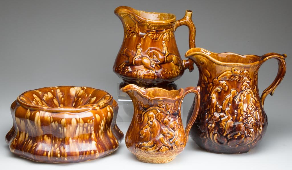 AMERICAN ROCKINGHAM-GLAZED POTTERY ARTICLES, LOT OF: AMERICAN ROCKINGHAM-GLAZED POTTERY ARTICLES, LOT OF FOUR, comprising a spittoon and three pitchers, one molded with children picking grapes, the others hunt related. Second half 19th century. 5" to 9"