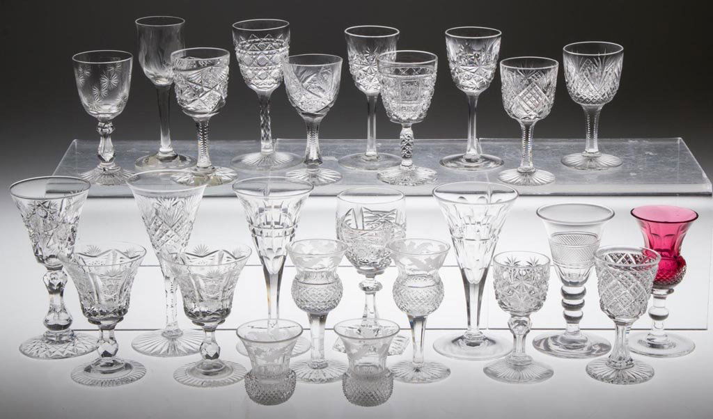 ASSORTED CUT-GLASS CORDIALS / WINE GLASSES, LOT OF 25: ASSORTED CUT-GLASS CORDIALS / WINE GLASSES, LOT OF 25, colorless, one red cased, including American brilliant-cut examples and British examples. Late 19th and 20th century. 1 7/8" to 4 1/2" H. Provena