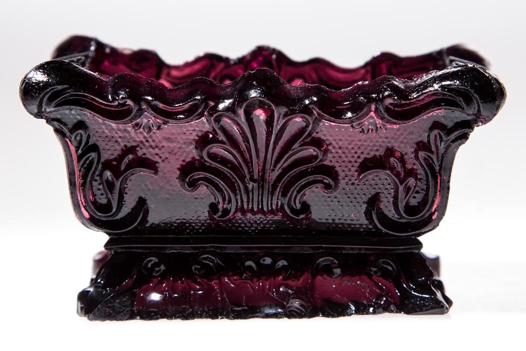 SL-1 SHELL PRESSED OPEN SALT: SL-1 SHELL PRESSED OPEN SALT, deep red amethyst, shaped rim. Extremely rare. Possibly Boston & Sandwich Glass Co. 1835-1850. 1 5/8" H, 2" x 3". Literature: Neal, p. 403. Parallels B & K I, fig. 1457. 
