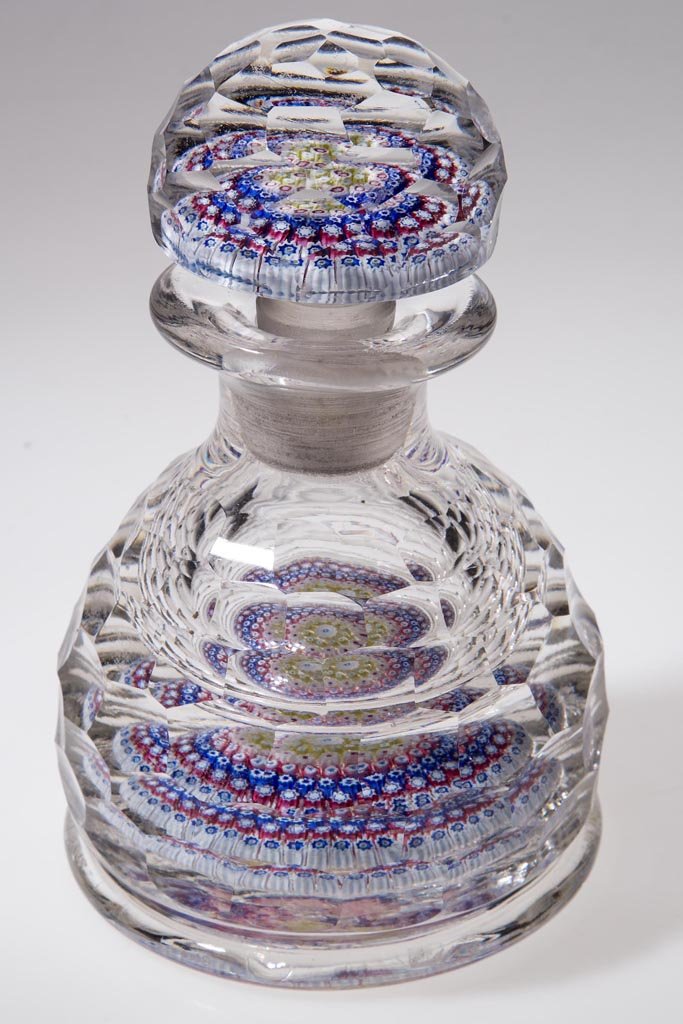 CONCENTRIC MILLEFIORI PAPERWEIGHT INK / COLOGNE BOTTLE: CONCENTRIC MILLEFIORI PAPERWEIGHT INK / COLOGNE BOTTLE, facet-cut surface on bottle and stopper, base with rough pontil mark. 20th century. 5 3/4" HOA, 3 5/8" D base. Provenance: Collection of Jessie 