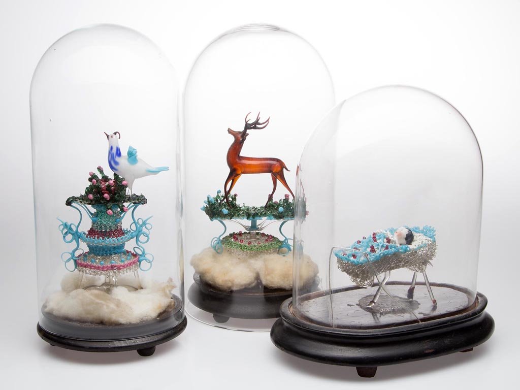 VICTORIAN LAMPWORK SCULPTURES UNDER GLASS, LOT OF THREE: VICTORIAN LAMPWORK SCULPTURES UNDER GLASS, LOT OF THREE, comprising a Frozen Charlotte china doll in cradle, a bird at nest, and a stag, each on a wooden base, covered with one original dome and two d