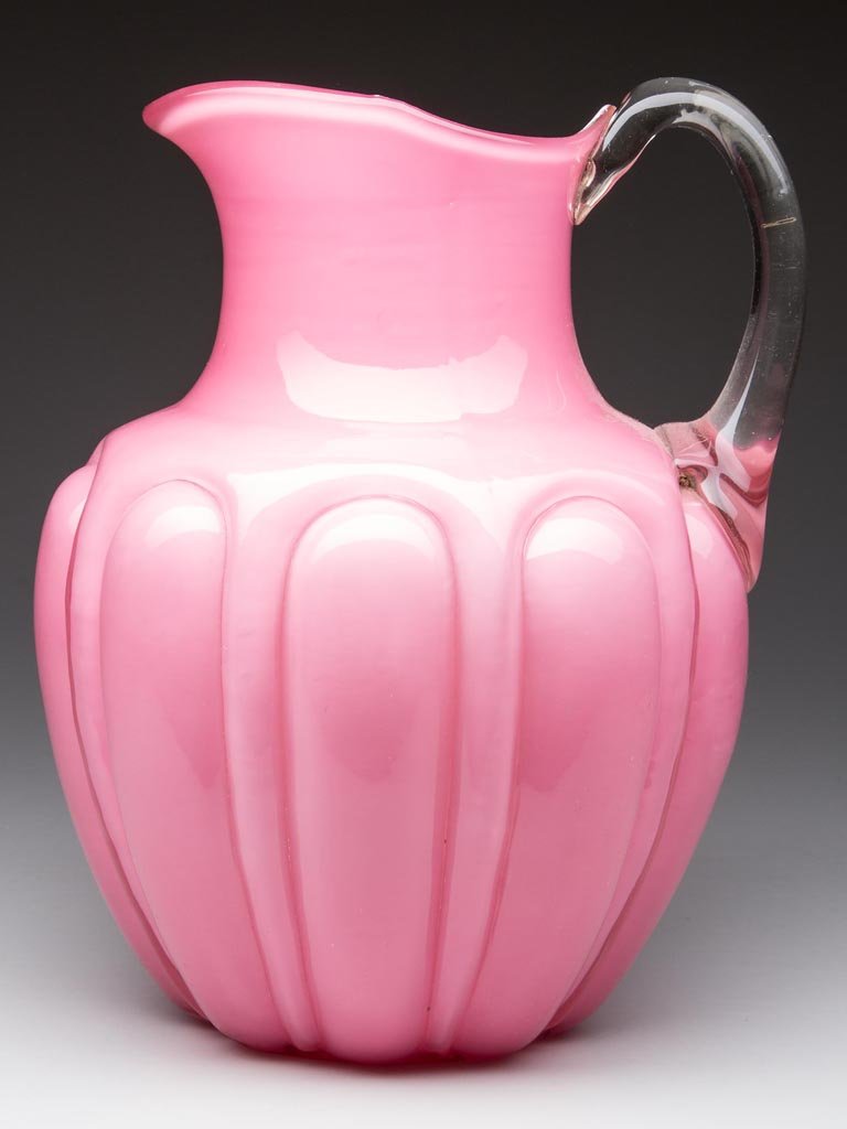 BULGING LOOPS WATER PITCHER: BULGING LOOPS WATER PITCHER, opal cased pink, colorless, applied handle, polished pontil mark. Consolidated Glass Co. Fourth quarter 19th century. 9 1/4" HOA.