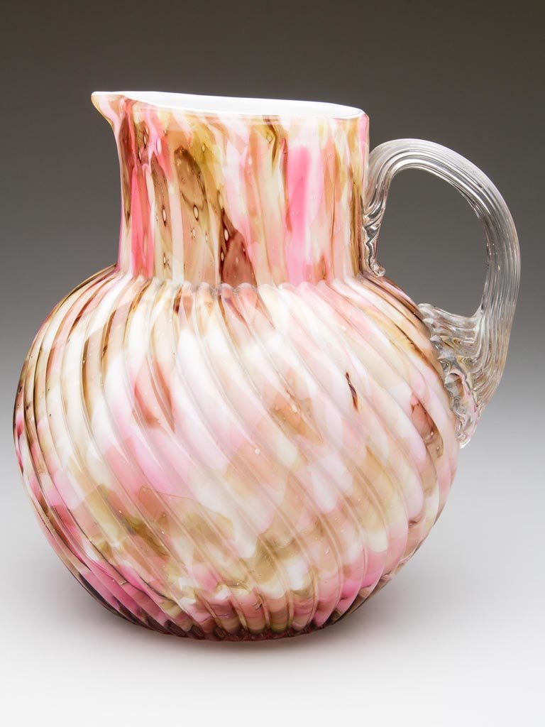 CASED SWIRLED RIB WATER PITCHER: CASED SWIRLED RIB WATER PITCHER, rose and olive spatter, globular body with plain rim, colorless applied reeded handle and polished pontil mark. Fourth quarter 19th century. 7 1/2" H. Provenance: From